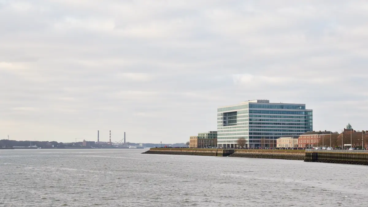 Generic image of a modern office building on an estuary with a wide, overcast sky.